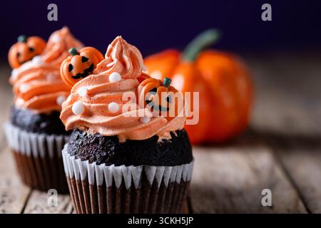 Halloween Cupcakes mit Kürbisdekor auf Holztisch Stockfoto