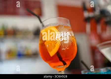Crema, Italien - 25. August 2025 Ein erfrischender, lebendiger Orangen-Aperitif-Cocktail, garniert mit einer frischen Scheibe Zitrusfrüchte und einem dunklen Strohhalm Stockfoto