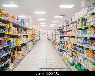 Cremona, Italien 10. September 2025 geräumiger Supermarktgang mit Reihen verpackter Lebensmittelprodukte, beleuchtet durch obenliegende Leuchtstofflampen, Stockfoto