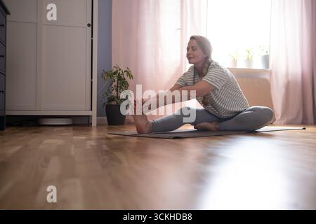 40-jährige Frau, die zu Hause Yoga, Dehnübungen und Hüftöffnungsübungen macht Stockfoto