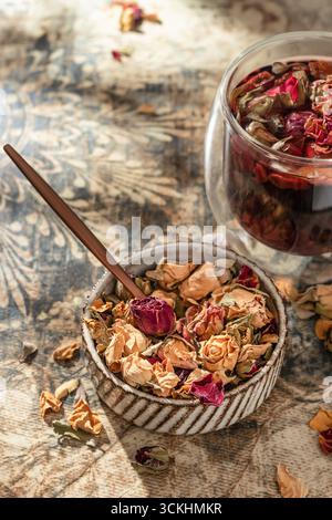 Rosenknospentee in Glasbecher mit getrockneten Rosenknospen auf orientalischem Hintergrund. Gesunder Blumentee. Vertikal Stockfoto
