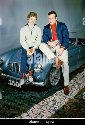 Ingemar Johansson und Birgit Lundgren mit dem Austin-Healey 3000In diesem legendären Schnappschuss aus dem Jahr 1959 sitzen der schwedische Schwergewichtsmeister Ingemar „Ingo“ Johansson (1932–2009) und seine Verlobte Birgit Lundgren auf einem eleganten Austin-Healey 3000, einem führenden britischen Sportwagen. Der 1959 von der Donald Healey Motor Company unter BMC eingeführte 3000 hatte einen 2,9-Liter-Reihensechszylinder-Motor mit bis zu 150 ps, Scheibenbremsen und einer Höchstgeschwindigkeit von über 120 km/h, was Leistung und Eleganz miteinander verbindet. Nachdem er 1959 Floyd Patterson geschlagen hatte, um den Titel im Schwergewicht zu gewinnen, verkörperte Johansson den Star-G-Titel Stockfoto
