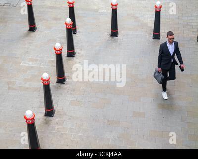 Gut gekleidete männliche Spaziergänge zwischen City of London Grenzpfollern, in London, Großbritannien Stockfoto