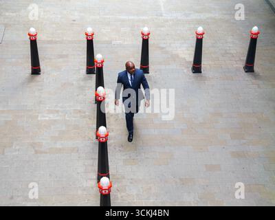 Gut gekleidete männliche Spaziergänge zwischen City of London Grenzpfollern, in London, Großbritannien Stockfoto
