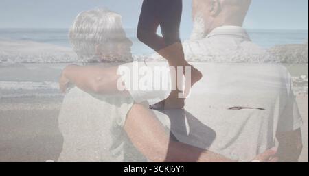 Reifer Mann und ältere Frau, die am Sandstrand stehen, mit einer umlaufenden Silhouette in Leggings Stockfoto