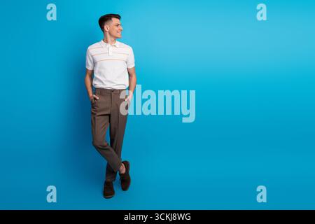 Selbstbewusster junger Mann, der vor einem leuchtend blauen Hintergrund steht, in lässiger und doch eleganter Kleidung gekleidet, die Stil und Charme ausstrahlt Stockfoto