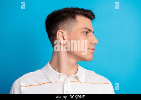 Porträt eines jungen gutaussehenden Mannes in einem weißen Poloshirt, das vor einem hellblauen Hintergrund steht und einen stilvollen Look hat Stockfoto