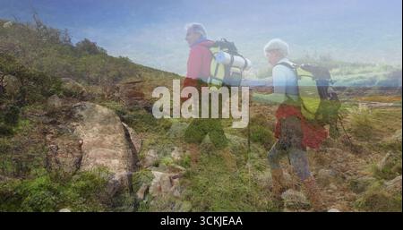 Trekking zwei ältere Wanderer auf einem zerklüfteten Bergpfad mit großen Rucksäcken und Trekkingstöcken Stockfoto