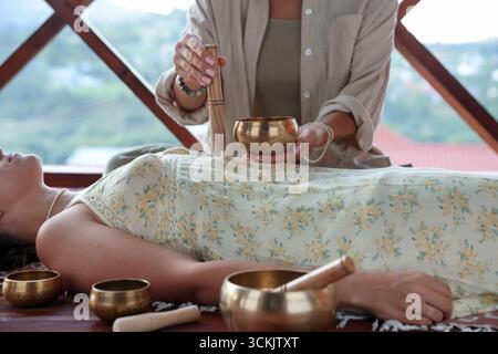 Frau, die sich einer Klangschüssel unterzieht, liegend auf dem Boden drinnen, Nahaufnahme Stockfoto