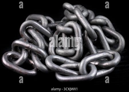 Stapel von Eisenketten isoliert auf dunklem Hintergrund. Stockfoto