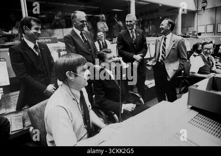 HOUSTON, TEXAS, USA - 13. November 1981 - US-Präsident Ronald Reagan wird von den NASA-Beamten in Mission Control lachen, als er scherzhaft Crew-Mitglieder, Astronauten Joe Engle und Richard fragt, ob sie auf dem Weg zu ihrem kalifornischen Landeplatz in Washington vorbeikommen könnten, damit er mitkommen könnte. Die STS-2-Crew war an ihrem nächsten Tag im Orbit, als das Gespräch stattfand. Von links nach rechts: Terry J. Hart, stellvertretender NASA-Administrator Dr. Hans Mark, NASA-Administrator James M. Beggs, JSC-Direktor Dr. Christopher C. Kraft Jr. Von links nach rechts sitzend: CAPCOM, Astronaut Stockfoto