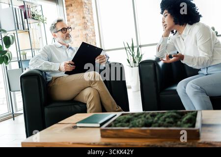 Professionelles Treffen in modernem Büroumfeld mit verschiedenen Kollegen, die Geschäftsstrategien und unternehmerische Ziele diskutieren Stockfoto