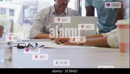 Professionelle Mitarbeiter, die Dokumente rund um den Laptop im Sitzungssaal prüfen, mit Smartphone-Symbolen Stockfoto