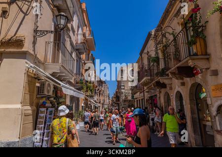 Venedig, Italien - 23. Juli 2024: Historische Straße in der Altstadt von Taormina, Sizilien. Touristen, die einen sonnigen mediterranen Tag genießen. Stockfoto