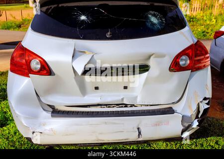 Das geparkte Fahrzeug weist erhebliche Schäden am Heck auf, die durch Kratzer und Risse in den Scheinwerfern verursacht werden Stockfoto