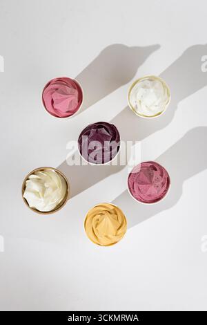 Verschiedene bunte Softeis in Pappbechern auf weißem Hintergrund, Draufsicht Stockfoto
