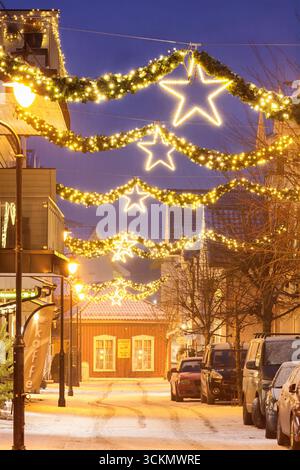 Langesund, Norwegen - 16. Dezember 2022: Weihnachtsbeleuchtung auf der Straße mit leuchtenden Sternen und festlicher Dekoration in einem charmanten Küstendorf W Stockfoto