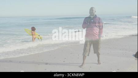 Er schlürft an einem Topf, der ein rotes Hemd an der Sandküste trägt, mit gelbem Surfbrett, Kopierraum Stockfoto