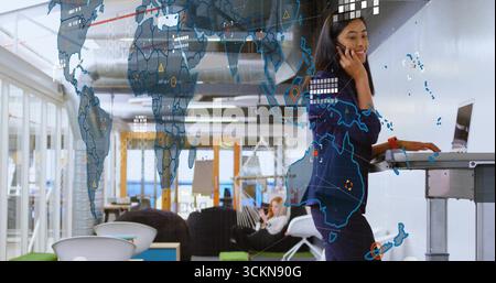 Asiatische Frau, die auf dem Handy am Stehpult im Büro spricht, mit digitaler Karte, Kopierraum Stockfoto