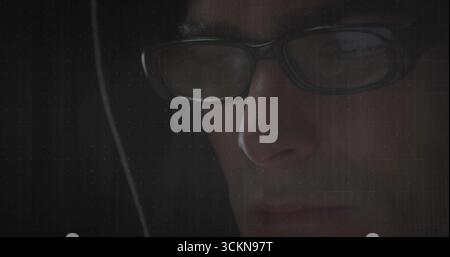 Mann mit rechteckiger Brille und Hoodie, der in dunklem Raum starrt, Gitterüberlagerung, Kopierraum Stockfoto