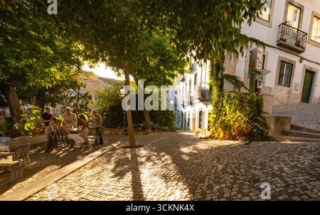 Geheimes Lissabon: Einheimische versammeln sich auf einem baumumschatteten Platz im Bezirk Misericórdia, Lissabon, Portugal, in der Dämmerung Stockfoto