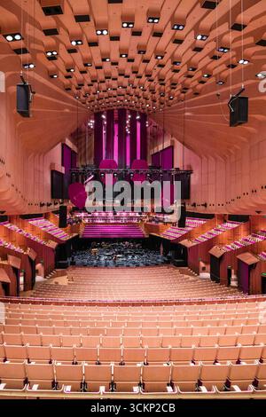 Herrlicher Innenblick auf die Konzerthalle des Opernhauses von Sydney mit Sitzreihen, lebhaften Farben und Bühnenaufteilung. Das architektonische Design betont Stockfoto