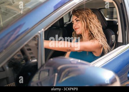 Junge blonde Frau genießt und lächelt in Blue Car. Hochwertige Fotos Stockfoto