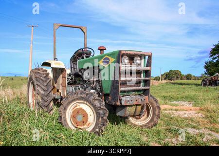 Landwirtschaftlicher Traktor, lackiert mit der Flagge Brasiliens (Bandeira do Brasil), draußen auf dem Bauernhof in einem ländlichen Gebiet. Flachwinkelansicht. Stockfoto