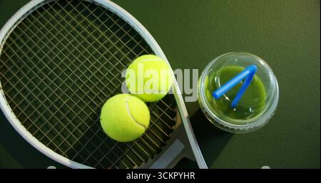 Tennisschläger und -Bälle auf der Bank, mit Deckel grüner Getränketasse, blauen Strohhalmen, Kopierraum Stockfoto