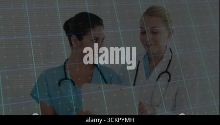 Überprüfung von zwei weiblichen medizinischen Mitarbeitern, die Patientendaten auf Tablette in der Klinik mit Stethoskopen untersuchen Stockfoto