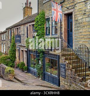 Typische Häuser und Geschäfte an der steilen Hauptstraße von Haworth, West Yorkshire Stockfoto