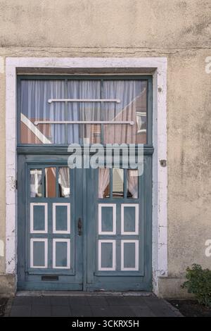 Blaue Holztür mit Fenstern und weißen Vorhängen auf einem rustikalen Gebäude, Altstadt Burgsteinfurt, Steinfurt, Münsterland, Nordrhein-Westfalen, Deutsch Stockfoto