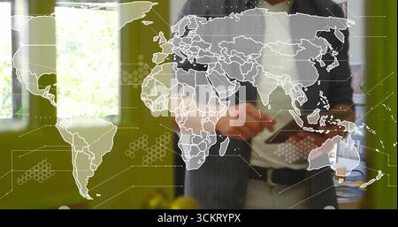 Geschäftsmann im Anzug, der ein Tablet im Büro mit grünen Wänden hält, mit digitaler Kartenüberlagerung Stockfoto