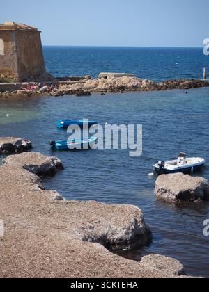 Fischerboote schwimmen auf dem blauen Meer in der Nähe der historischen Küstenmauer in Trapani Sizilien Italien Stockfoto