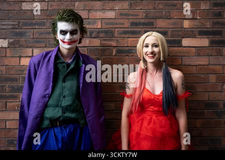 Ein hübsches Mädchen und ein hübscher männlicher Cosplayer, der Spaß hat und lacht, während er als Joker und Harley Quinn gekleidet ist, mit Kopierraum darüber Stockfoto