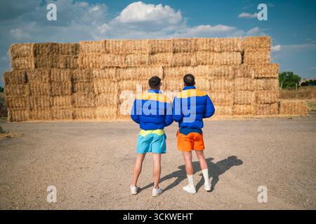 Zwei Männer stehen mit Rücken zu Heuballen Stockfoto