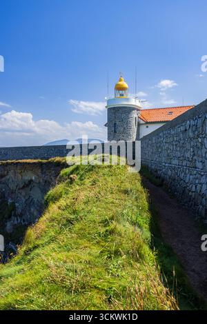 Malerischer Blick auf den historischen Leuchtturm von Cudillero, der auf einer grasbewachsenen Klippe mit Blick auf die Biskaya-Bucht in Asturien, Spanien, steht Stockfoto
