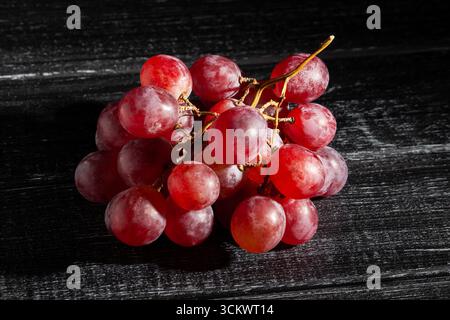 Rote Traube auf schwarzem Holzhintergrund Stockfoto
