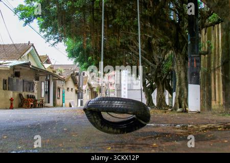 Taoyuan City, Taiwan - 1. Juni 2012: Eine verwitterte Reifenschaukel hängt an einem großen Baum im Xian Guang Military Kindred Village Cultural Park. Alt Stockfoto
