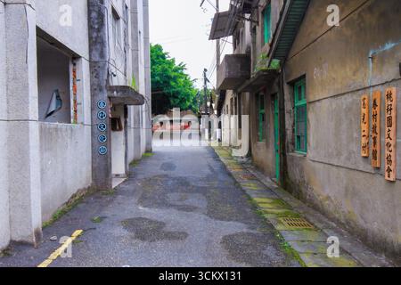 Taoyuan City, Taiwan - 1. Juni 2012: Eine enge, veraltete Gasse schlängelt sich durch den Xian Guang Military Kindred Village Cultural Park. Verwitterte Gebäude Stockfoto