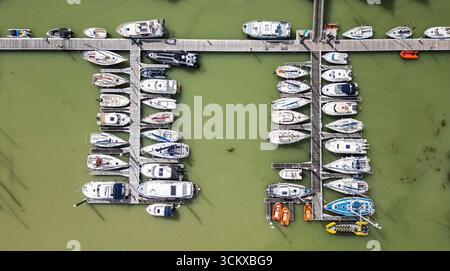 Drohnenansicht des Yachthafens in Saint-Valery-sur-Somme, Frankreich, mit Booten, die entlang hölzernen Piers im grünen Wasser liegen, einem malerischen Küstenhafen Stockfoto