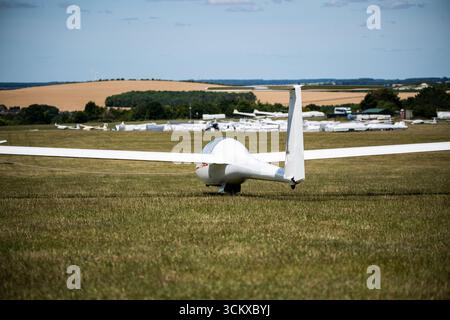 Weißer zweisitziger Segelflugzeug mit T-Heck auf einer Grasbahn auf einem Flugplatz, von hinten gesehen. Luftfahrt, Segelflugzeugsport und Trainingsflugzeuge. Stockfoto