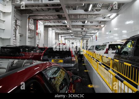 Autodeck auf einer Kreuzschienenfähre, die von Portsmouth nach Caen fährt und geparkte Fahrzeuge im Inneren des Schiffes zeigt, eine Szene europäischer Art Stockfoto