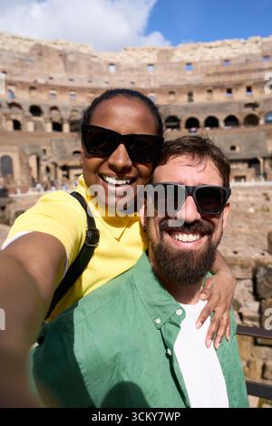Glückliches, vielfältiges Paar, das Selfie im Kolosseum in Rom macht Stockfoto