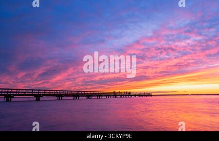 Am 13th Avenue Pier treffen sich die Menschen, um einen lebhaften, farbenfrohen Sonnenuntergang über der Barnegat Bay im Seaside Park, New Jersey, USA, zu beobachten. Stockfoto