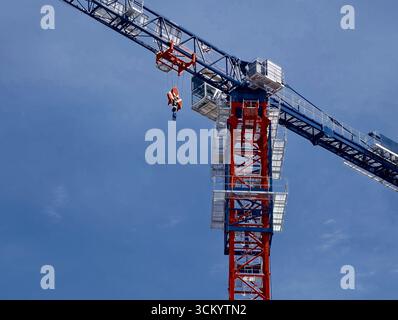 Baukran arbeitet an einem Bauprojekt unter klarem blauem Himmel in einer städtischen Umgebung Stockfoto