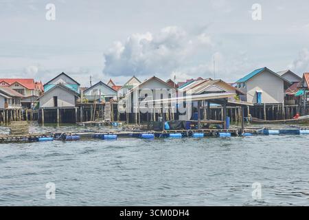 PHUKET, THAILAND - 12. NOVEMBER 2017: Tropisches Küstendorf mit bunten Pfahlhäusern am Meer unter bewölktem Himmel. Stockfoto