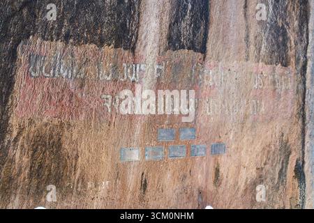 PHUKET, THAILAND - 12. NOVEMBER 2017: Historischer, antiker Felsstich mit verblasster Schrift und Plaketten auf verwitterter Oberfläche. Stockfoto