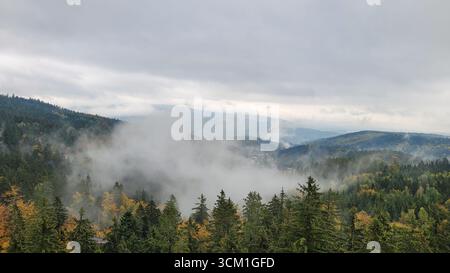 Moody Herbsthügel mit Wolken, die durch die Täler gleiten, vom Stezka Korunami Stromů (Baumwipfelpfad) im Krkonoše-Gebirge in Tschechien aus gesehen Stockfoto
