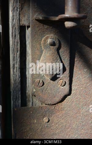 Schönes helles, trockenes Türschloss aus alten Metallteilen mit Rost, Löchern, Unebenheiten, Korrosion. Stockfoto